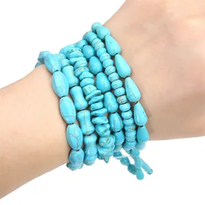 Pile de bracelets en perles de turquoise avec pierres irrégulières sur le poignet du modèle