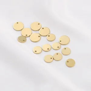Close-up of gold-plated copper round charm pendants on a white fabric background