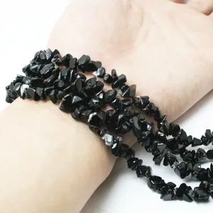 Primer plano de cuentas de piedra de cristal negro natural irregular en la muñeca