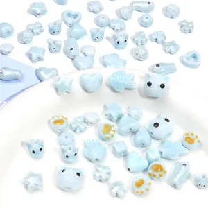 Détail macro de perles en céramique bleues en forme de chat, poisson et cœur pour bijoux