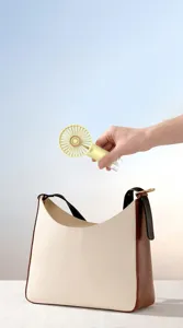 Draagbare mini USB oplaadbare ventilator geplaatst in een stijlvolle dameshandtas voor reis