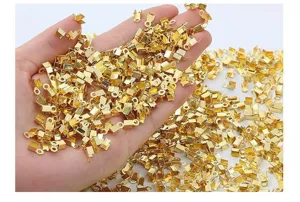 Hand die een grote hoeveelheid gouden koorduiteinden voor het maken van sieraden vasthoudt