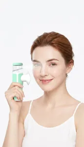 Handheld eye nebulizer for dry eye relief held by a smiling woman in a studio setting