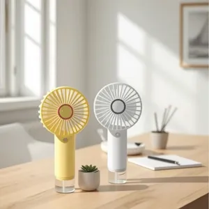 Ventiladores nebulizadores portátiles USB blancos y amarillos sobre un escritorio soleado.