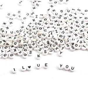Macro detail of white circular acrylic alphabet beads with black letters for DIY jewelry