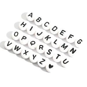 Close-up view of DIY white acrylic alphabet beads with black capital letters A-Z and heart icon