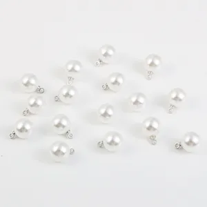 Vue détaillée de pendentifs en imitation perle ABS blanche avec œillets argentés pour le bricolage.