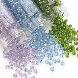 Gros plan de perles de verre de 4mm argentées en violet, bleu et vert sortant de bocaux.