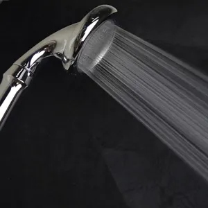 High-pressure chrome-plated shower head nozzle spraying water against a dark background