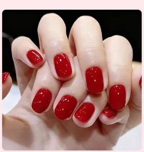 Gros plan d'un vernis à ongles en gel rouge brillant appliqué sur des ongles naturels
