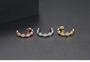 Dettaglio macro di eleganti orecchini ear cuff in zircone oro, argento e oro rosa lusso