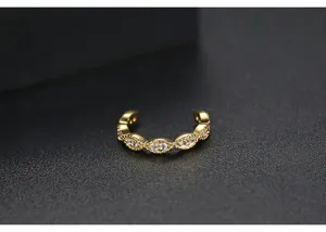 Dettaglio del ear cuff dorato con pietre di zircone marquise e bordi milgrain sottili
