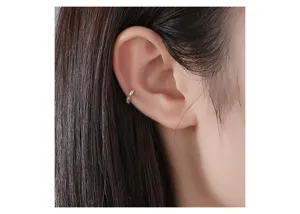 Dettaglio di un delicato ear cuff in zircone dorato indossato su un orecchio non forato