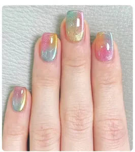 Detailed close-up of vibrant rainbow gradient glitter nails on a grey background