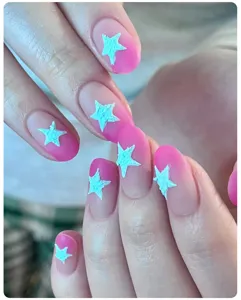 Macro detail of pink gradient manicure featuring 3D light blue textured star designs.
