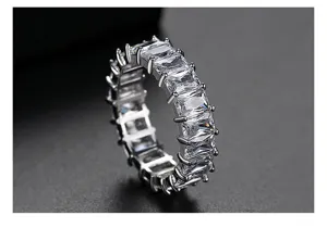 Macro detail of emerald-cut clear cubic zirconia eternity ring in silver finish.