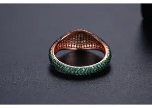 Vista detallada de anillo de oro rosa con pavé de cristales verdes estilo hip-hop