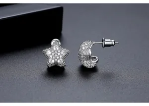 Detailed macro view of asymmetrical star and crescent moon stud earrings with pavé crystals.