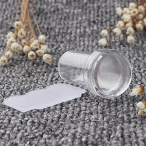 Nahaufnahme eines transparenten Nailart-Stempel-Sets mit Schaber auf grauem Hintergrund.