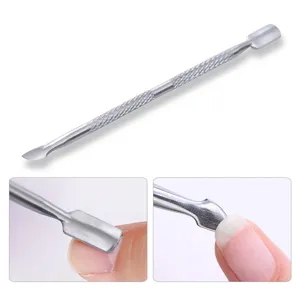 Macro view of a stainless steel double-ended nail cuticle pusher tool in use for manicure