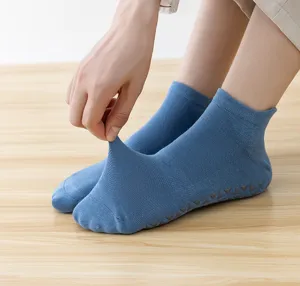 Close-up of breathable blue yoga socks with anti-slip silicone grippers on wooden floor.