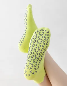 Close-up detail of anti-slip grey silicone grips on neon lime green Pilates yoga socks