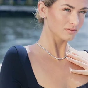 Elegant silver-toned tennis necklace worn by a model against a soft outdoor backdrop.