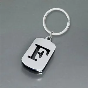 Close-up view of a minimalist stainless steel keychain with a cutout letter F design