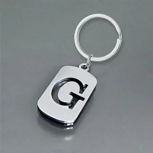 Macro detail view of a polished stainless steel keychain featuring a hollow letter G design