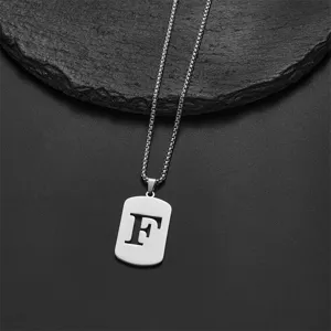 Detailed view of a stainless steel necklace with a hollow letter F cutout pendant on stone