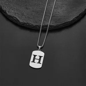 Close-up detail of a silver stainless steel rectangular pendant with hollowed letter H