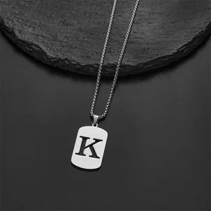 Detailed macro shot of stainless steel rectangular pendant with cutout letter K on box chain.