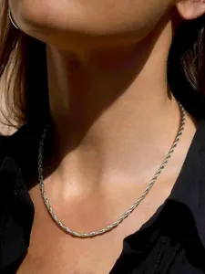 Primer plano de un collar de cadena de cuerda retorcida de plata en modelo real