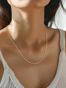 Primer plano de un collar de cadena de cuerda dorada minimalista con textura retorcida