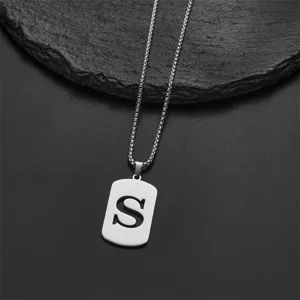 Close-up detail of a minimalist stainless steel dog tag necklace with cutout letter S