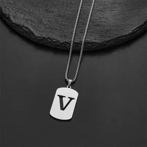 Macro detail of stainless steel necklace with cutout letter V pendant on slate background