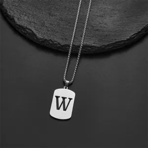 Close-up of stainless steel necklace with silver letter W pendant on black stone background