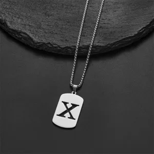 Detailed view of a stainless steel necklace featuring a cutout letter X pendant on black rock