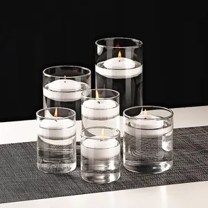 Elegante set van heldere glazen cilinder kandelaars met witte drijvende kaarsen