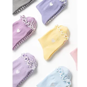 Close-up of pastel yoga socks with heart embroidery, lace ruffles and non-slip dots
