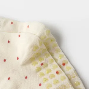 Macro detail showing glittery heart-shaped anti-slip silicone grips on cream yoga socks
