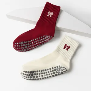 Close-up detail showing the hexagonal anti-slip grips and bow pattern on red and white yoga socks