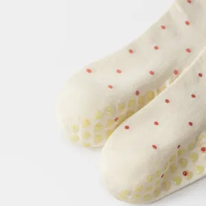 Detailed view of white polka dot yoga socks with yellow heart-shaped anti-slip grippers