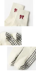 Detailed view of cream yoga socks featuring red bow accents and grey anti-slip grippers.