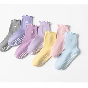 Non-slip yoga socks featuring ruffled edges and heart embroidery in pastel colors.