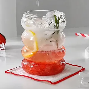 Detail shot of a wavy borosilicate glass cup with a layered drink and fruit garnish.