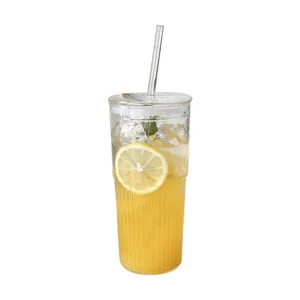 Nahaufnahme eines geriffelten Glasbechers mit Zitronensaft, Glasstrohhalm und Deckel