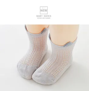 Nahaufnahme grauer atmungsaktiver Mesh-Babysocken mit rutschfester Sohle für Sommer
