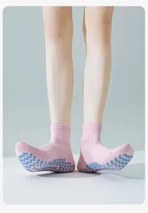 Dettaglio calzini da yoga rosa con punti di presa antiscivolo in silicone blu sulla suola.