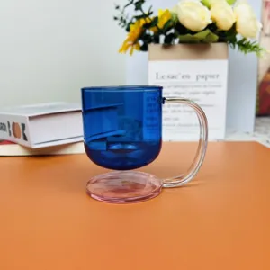Close-up detail of a blue suspended glass coffee mug with a pink base on an orange table